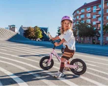 Dziecko uczące się jazdy na rowerku biegowym dopasowanym do wzrostu i długości nóg